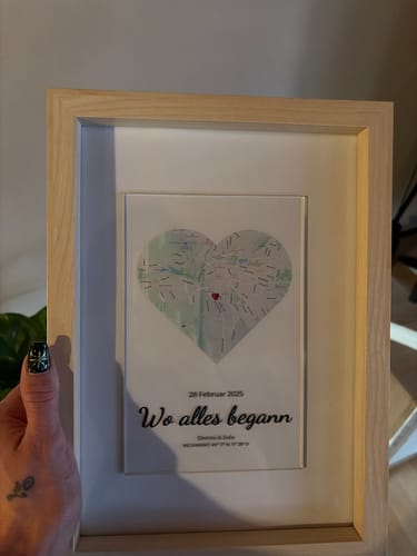 Kunde hält die personalisierte Acryltafel „Unser Ereignis“ in einem schönen Holzbilderrahmen.