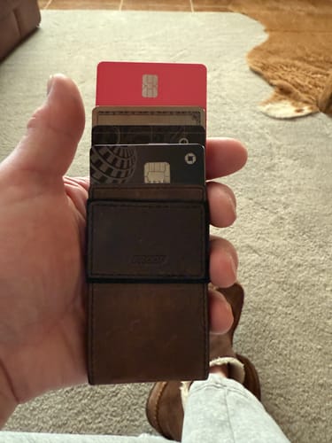 Reviewer holding a slim wallet, with the red SPOTMINDERS Tracking Card visible among other cards.