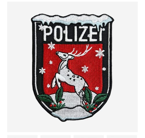 Ein Kunde zeigt den weihnachtlichen Polizei-Textilpatch mit einem springenden Reh auf rotem Grund.