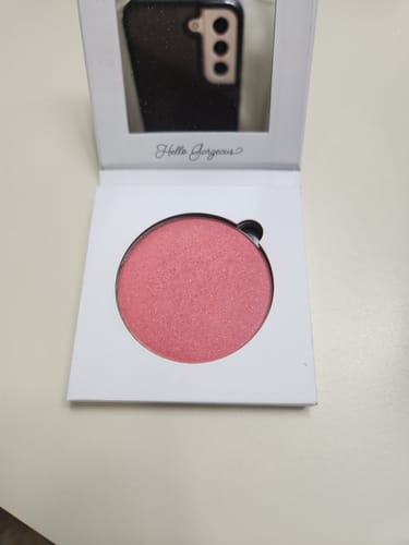 Reviewer's open compact of shimmery pink Blush, showing the mirror and "Hello Gorgeous" text inside the lid.