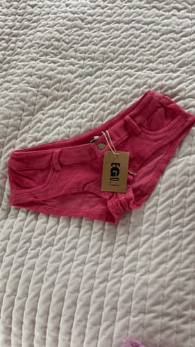 Customer's new pink Micro Mini Shorts with tags still attached, laid flat on a white textured surface.