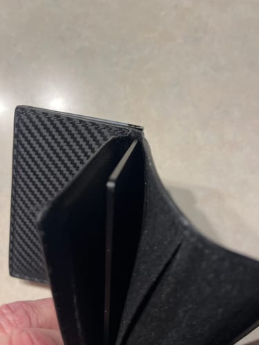 Customer holding a black wallet open to show the thin SPOTMINDERS Tracking Card in a slot.