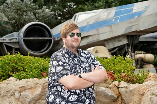 Customer posing in the black and white 'Hawaiian Hijinks' shirt at a theme park.