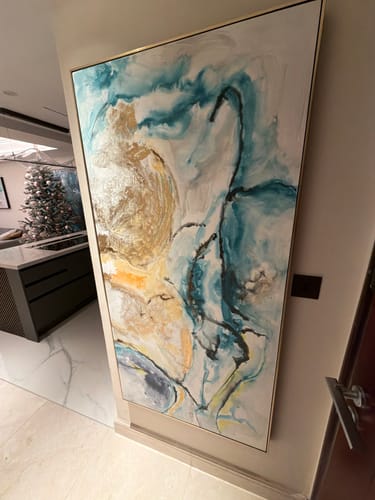Customer's Hand Painted Art Painting with a gold frame hanging on a wall, showing abstract swirls of teal, white, and gold.