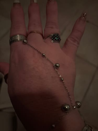 Close-up: Reviewer's hand wearing several rings, including what appears to be the silver Angelica® Angel Number Band.