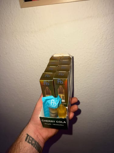 A customer holds a box of 10 RandM Nic Salts in the Cherry Cola flavor.