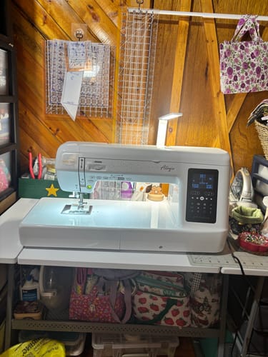 Customer's Babylock Allegro Sewing & Quilting Machine on a desk in a craft room, its large workspace illuminated.