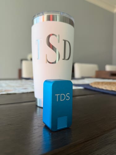 Customer's blue Ikigai Case Nano Vitamin Case with engraved 'TDS' initials, sitting on a dark table.