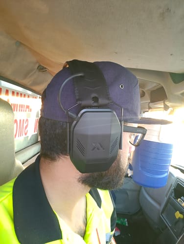 Reviewer wearing the black MX PRO earmuffs over a cap while inside a vehicle.