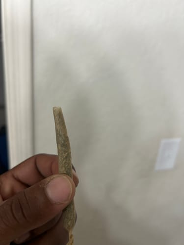 Customer's hand holding a slender, hand-rolled joint of Wedding Cake.