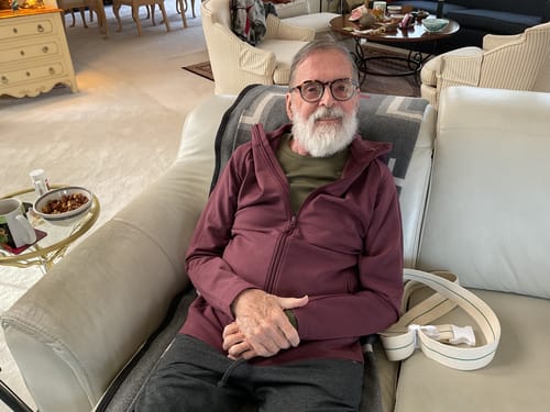 Reviewer sitting on a couch wearing the comfortable Boulder Hoodie in Grape Harvest.