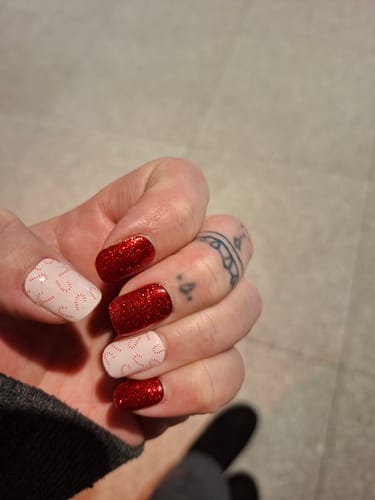 Customer's hand showing a manicure from the Holy Gels kit with alternating sparkly red and pink candy cane patterned nails.