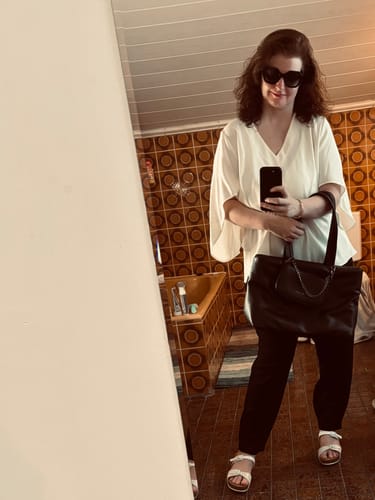 Rezensentin trägt den Clover Deluxe Armreif am Handgelenk in einem Ganzkörper-Spiegelselfie.