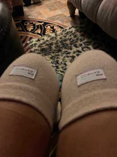 Customer's point-of-view looking down at a pair of beige Premium Bamboo Knee Sleeves being worn.