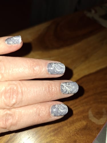 Nahaufnahme der Hand einer Kundin mit den 'Grey Frost' Nagelfolien auf kurzen Nägeln.