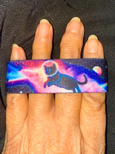 Customer's I Knead My Space Bracelet on their hand, showing a black cat in a colorful galaxy.