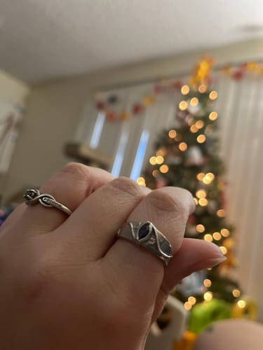 Customer wearing the silver September Birthstone Ring with a textured leaf-like band and dark blue center stone.
