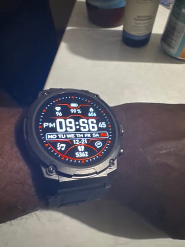 Reviewer's close-up of the black Gard Pro Ultra 3 watch on their wrist, displaying a digital face with health metrics.