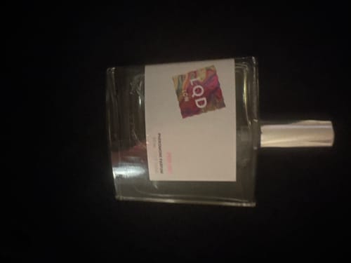 A customer's bottle of For Her Pheromone Perfume, which is nearly empty, lying on a dark surface.