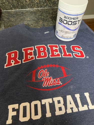 Reviewer's container of Boomer Boost sitting on an Ole Miss Rebels football t-shirt.