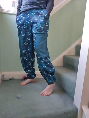 Reviewer standing on stairs wearing comfy lounge pants made from the blue Galaxy Cats fabric.