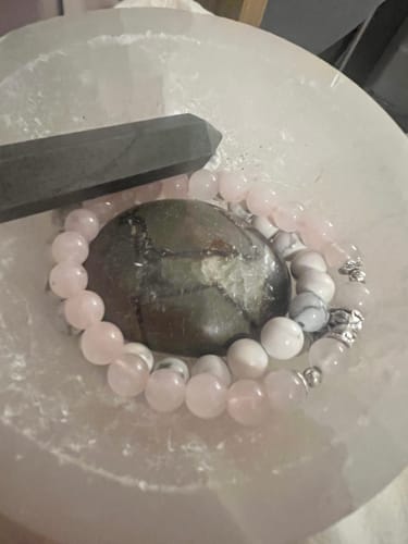 Reviewer's crystal bracelets and stones from the VIP Crystal Club arranged in a white charging bowl.