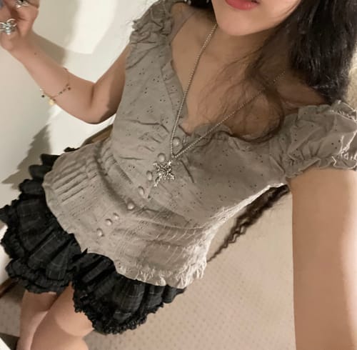 Reviewer wearing the Oveline Shadow Grey Eyelet Ruffle Blouse with a dark ruffled skirt and silver necklace.