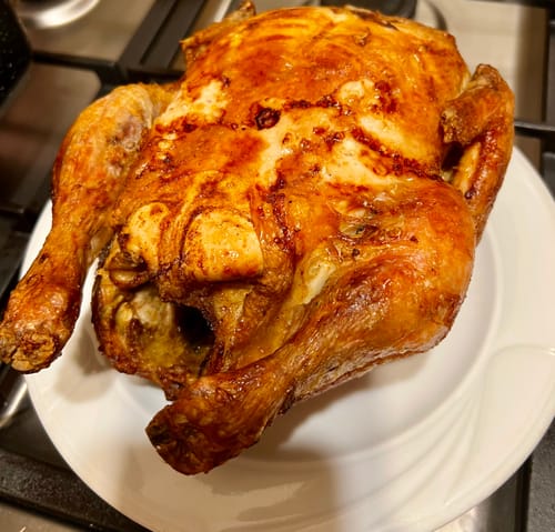 Recenzent arătând un pui întreg rumenit, gătit cu friteuza Air Fryer Novio StonePro.