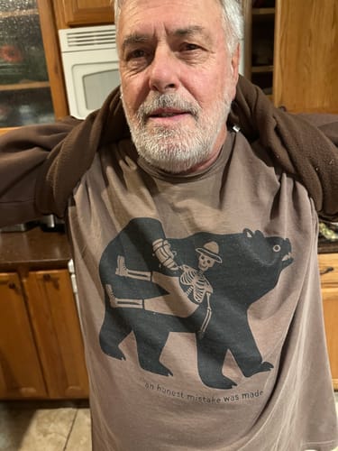 Customer wearing the brown Honest Mistake T-Shirt, showing the front graphic of a skeleton riding a bear.