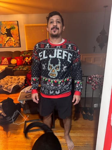 A customer wearing the EL JEFE Navidad Sweatshirt indoors, showing off the full front design.