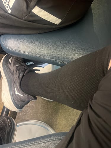 A reviewer's lower leg and foot wearing the black, ribbed Performance Eucalyptus Compression Socks.
