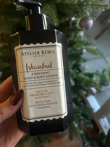 Een klant houdt de zwarte fles Istanbul Hand & Bodylotion vast voor een kerstboom.