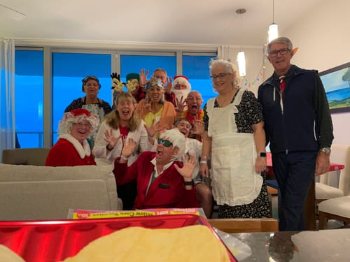 A group of customers in festive costumes posing for a photo while playing the Christmas Crime Murder Mystery Game.