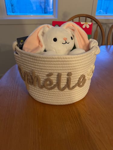 Customer's personalized white knitted basket with the name Amélie and a flower icon, filled with a stuffed bunny.
