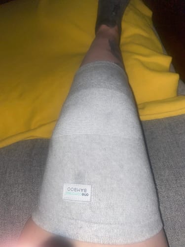 Reviewer showing the fit of the light grey Premium Bamboo Knee Sleeve on their leg while sitting down.