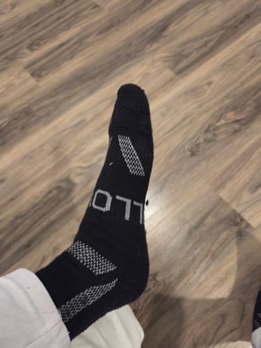 Reviewer showing the fit of their black Men's Alpaca Socks with grey patterned details.