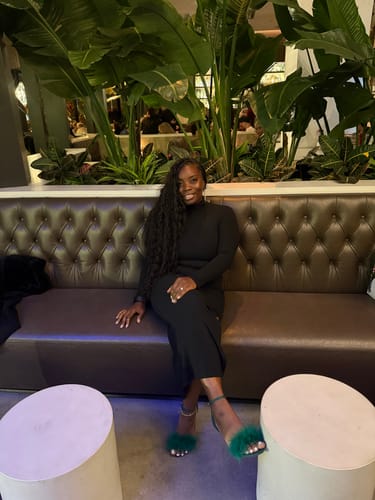 A reviewer smiling while seated, showing off her long, deep wave hairstyle with Loose Deep Wave Human Crochet Hair.