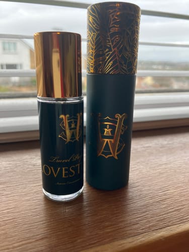 Customer's small bottle of Lovestory perfume with its dark green and gold case on a wooden surface.