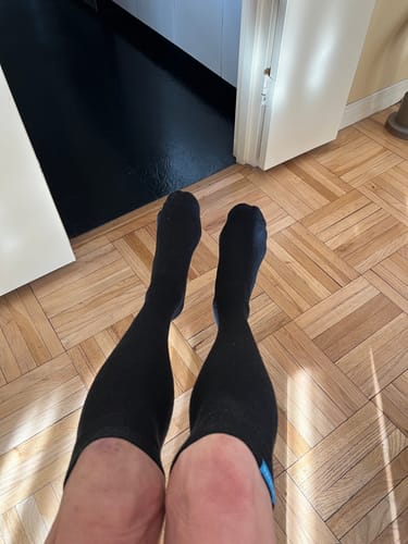 Reviewer's view of their legs wearing the black Performance Eucalyptus Compression Socks indoors.
