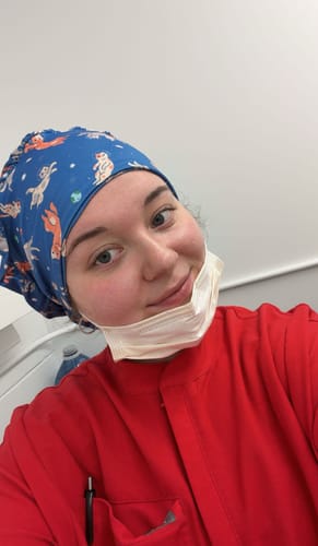 Reviewer in red scrubs wearing the blue, animal-patterned DuoStyle Scrub Hat.