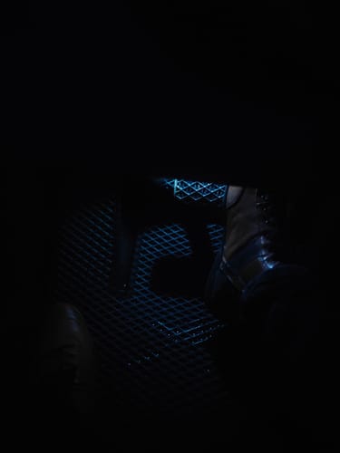 Widok częściowy: czarny dywanik samochodowy klienta w słabo oświetlonym wnętrzu samochodu.