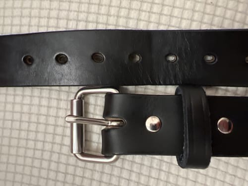 A close-up of the reviewer's black leather Gunner belt, laid flat to show the stainless steel buckle and belt holes.