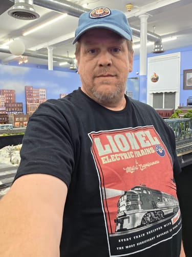 Customer wearing the black Magne-Traction Lionel Trains T-Shirt in front of a model train display.