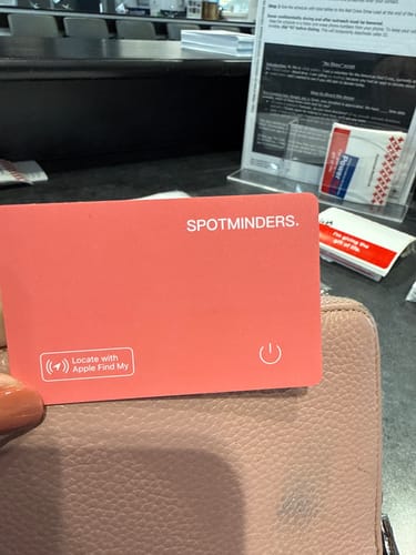 Customer holding the coral SPOTMINDERS tracking card over a pink purse.