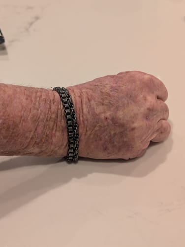 Close-up of a customer's wrist wearing a sturdy, dark chain link bracelet.