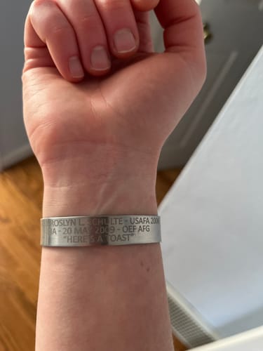 A reviewer's wrist wearing a sturdy, stainless steel bracelet with custom engraving.