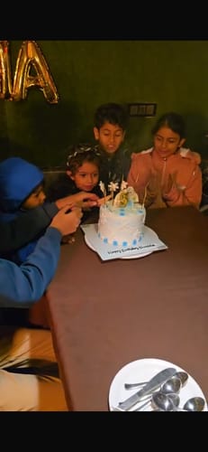 Customer's children gathered at a table, cutting into the white and blue Frozen Birthday Cake.