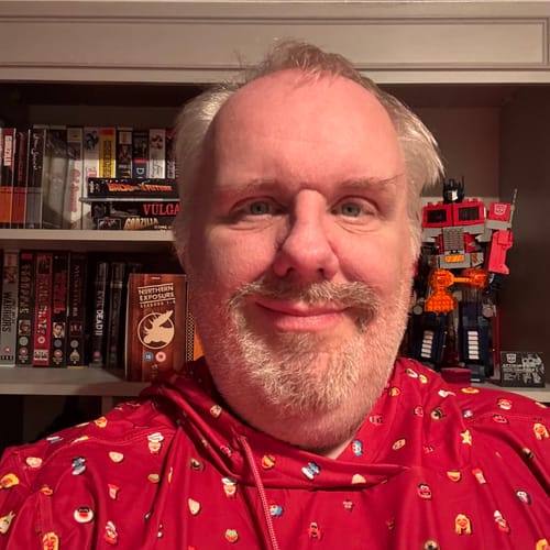 Reviewer in a close-up shot wearing the red "Lil Muppets" Performance Hoodie with its all-over character print.