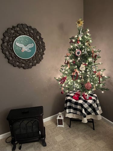 Customer's round Philadelphia Eagles artwork hanging on a wall next to a small Christmas tree.