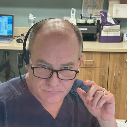 A customer, who identifies as a nurse, at his desk wearing a headset and scrubs.